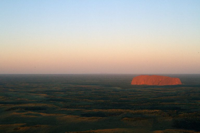 Uluru as seen from the air during a sunset helicopter ride. Discover the best things to do at Uluru.