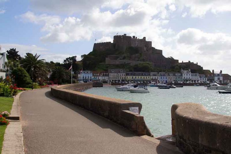 View of the town of Gorey, with the castle Mont Orgueil looming over the town. Discover the best things to do in Jersey, Channel Islands.