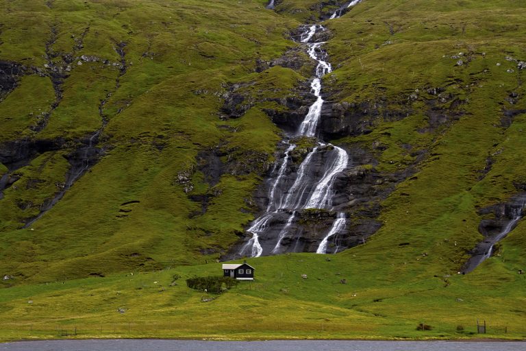 A house in the Faroe Islands, with a waterfall behind it. This Faroe Islands travel guide will help you plan a fabulous trip to this remote archipelago.