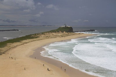Nobbys Beach in Newcastle with the lighthouse at its head. Walking along this beach is one of the best things to do in Newcastle.