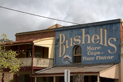 Shopfronts in the main street of Maldon, featuring historic ads such as a vibrant sign for Bushells Tea. Discover unmissable things to do in Maldon.