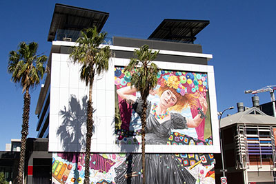 'She Imagined Buttons' (2020) by Jasmine Crisp, a mural of musician Sia Fuller painted on the side of the Rockford Hotel in Adelaide. It depicts Sia in a black dress, surrounded by colourful buttons. The mural is part of the Adelaide City of Music Laneways project.