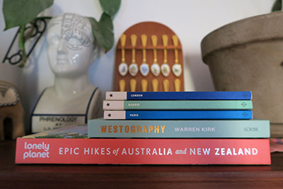 Coffee table travel books sitting on top of a bookshelf.
