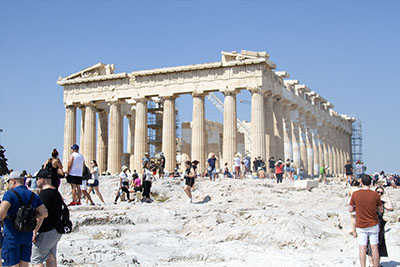 Tourists in front of the Parthenon, on the Acropolis in Athens on a sunny day. Discover how to not look like a tourist in Europe.