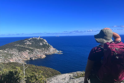 A hiker looks out at the lightstation of Wilsons Prom.